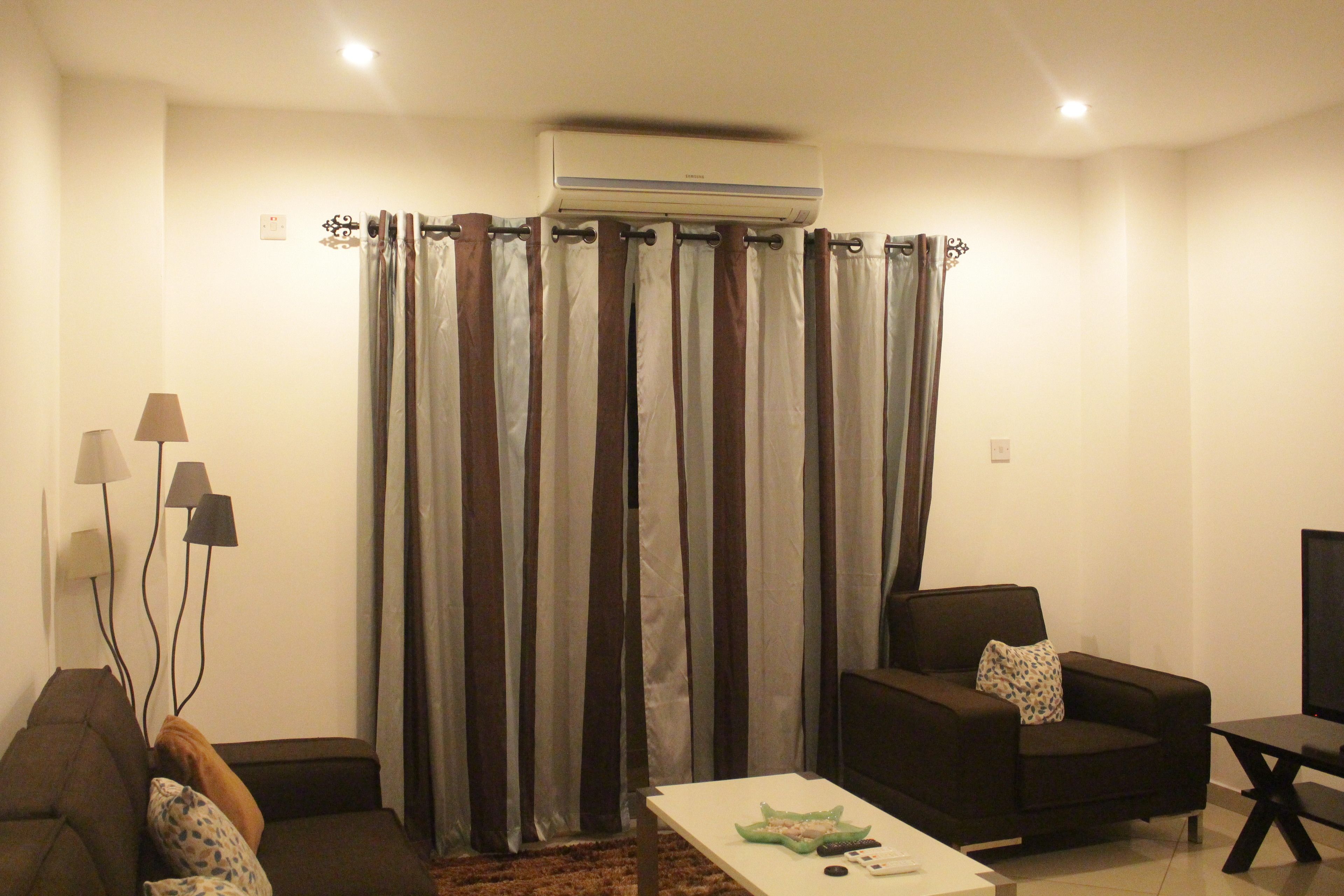 Una sala de estar con un sofá, una mesa de centro, un televisor y un aire acondicionado instalado en la pared.
