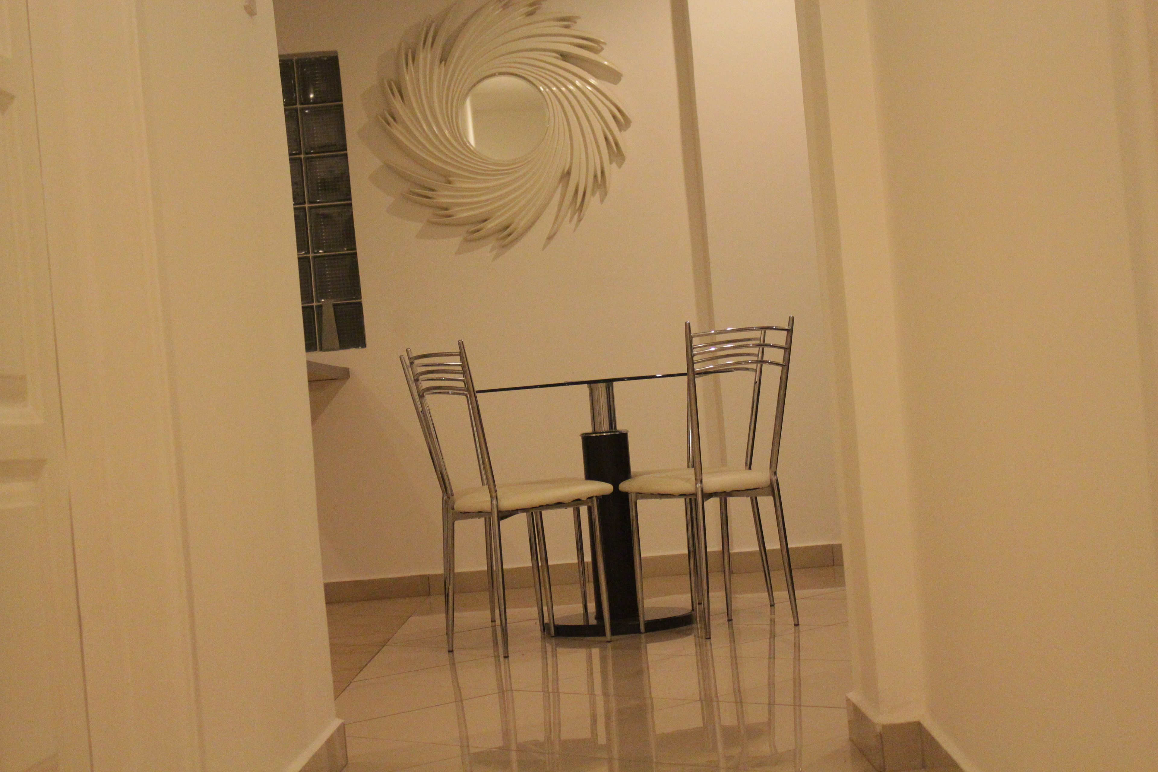 Un couloir qui mène à un espace repas comprenant une table ronde et quatre chaises.