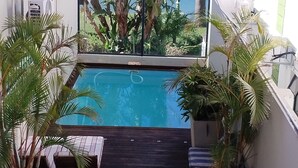 A rooftop pool area with a view of a body of water and surrounding greenery.
