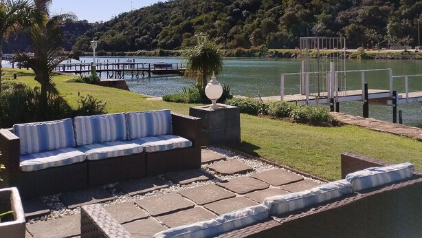 A patio with outdoor seating, a pool, and a view of a lake and hills.