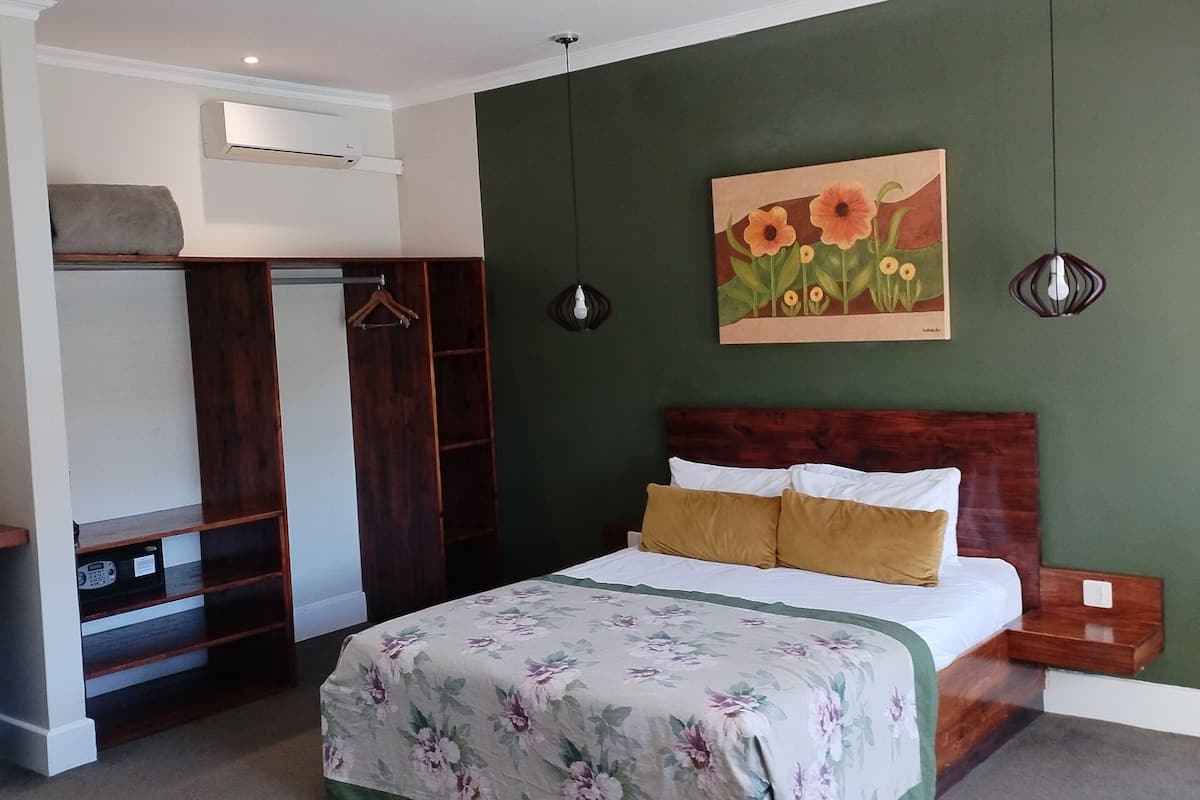 Ein Schlafzimmer mit Bett, Kleiderschrank, Klimaanlage und einem Bild an der Wand.