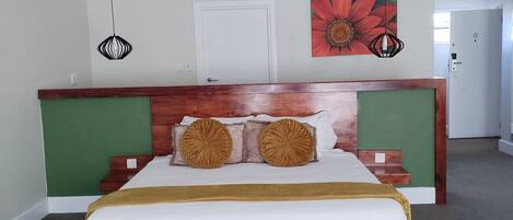 Un dormitorio con una cama de madera, paredes de acento verde y una obra de arte floral grande.