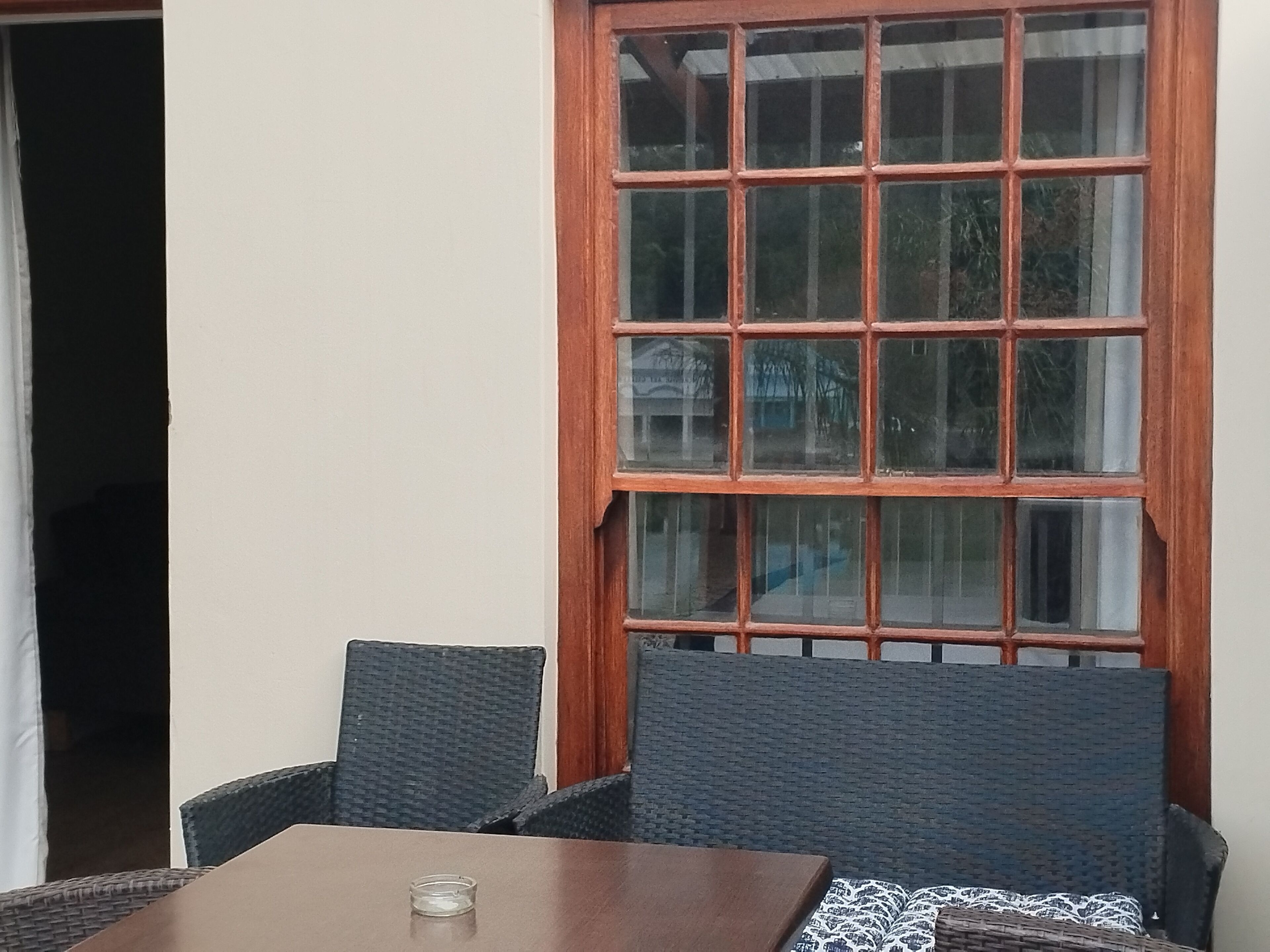Habitación de esquina con una mesa de madera y dos sillas de mimbre.