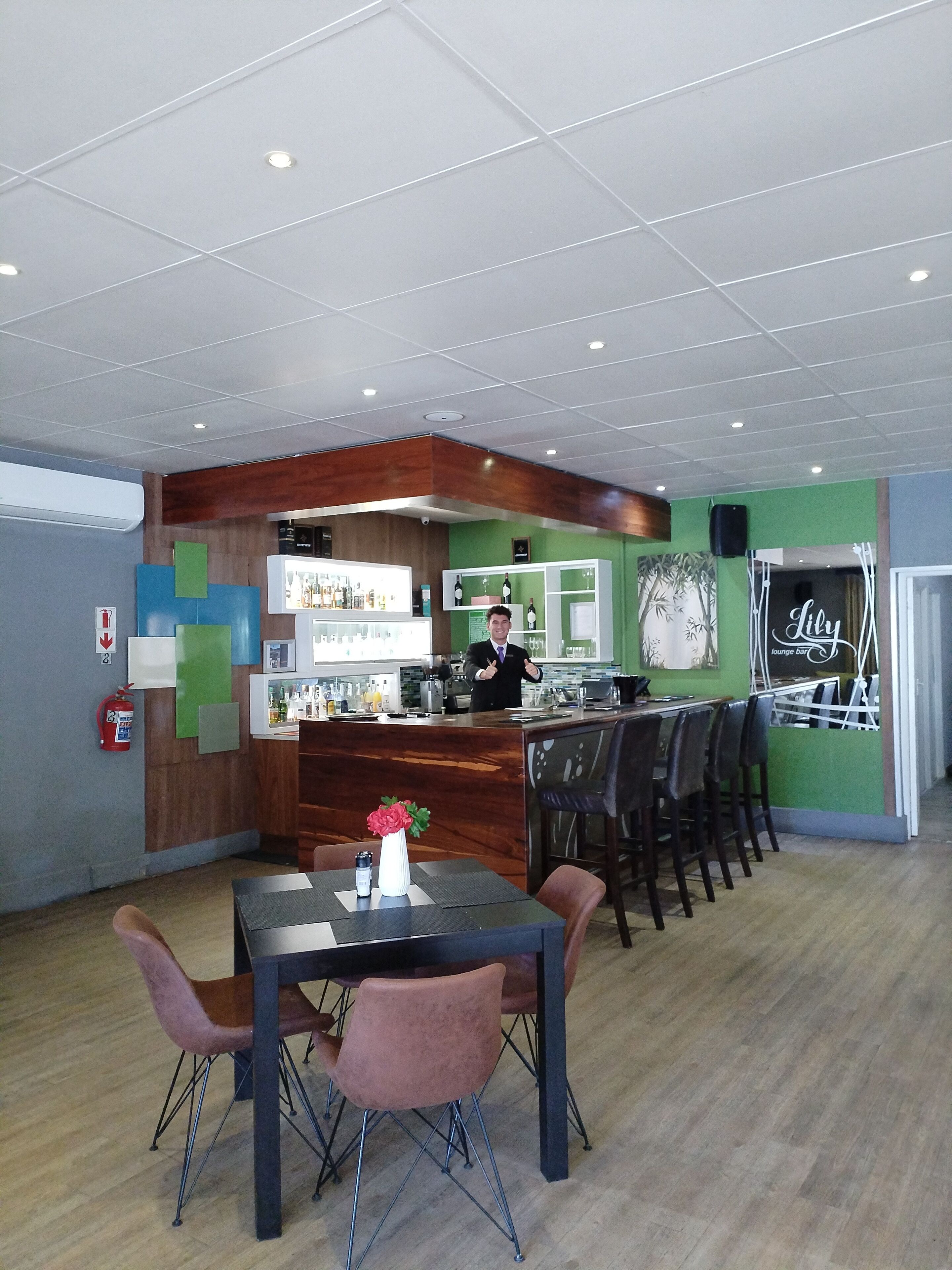 Un restaurante con zona de bar, techo de madera y paredes verdes.