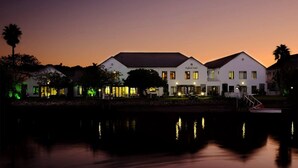 A waterfront hotel with multiple buildings, a dock, and a calm lake reflecting the structures.