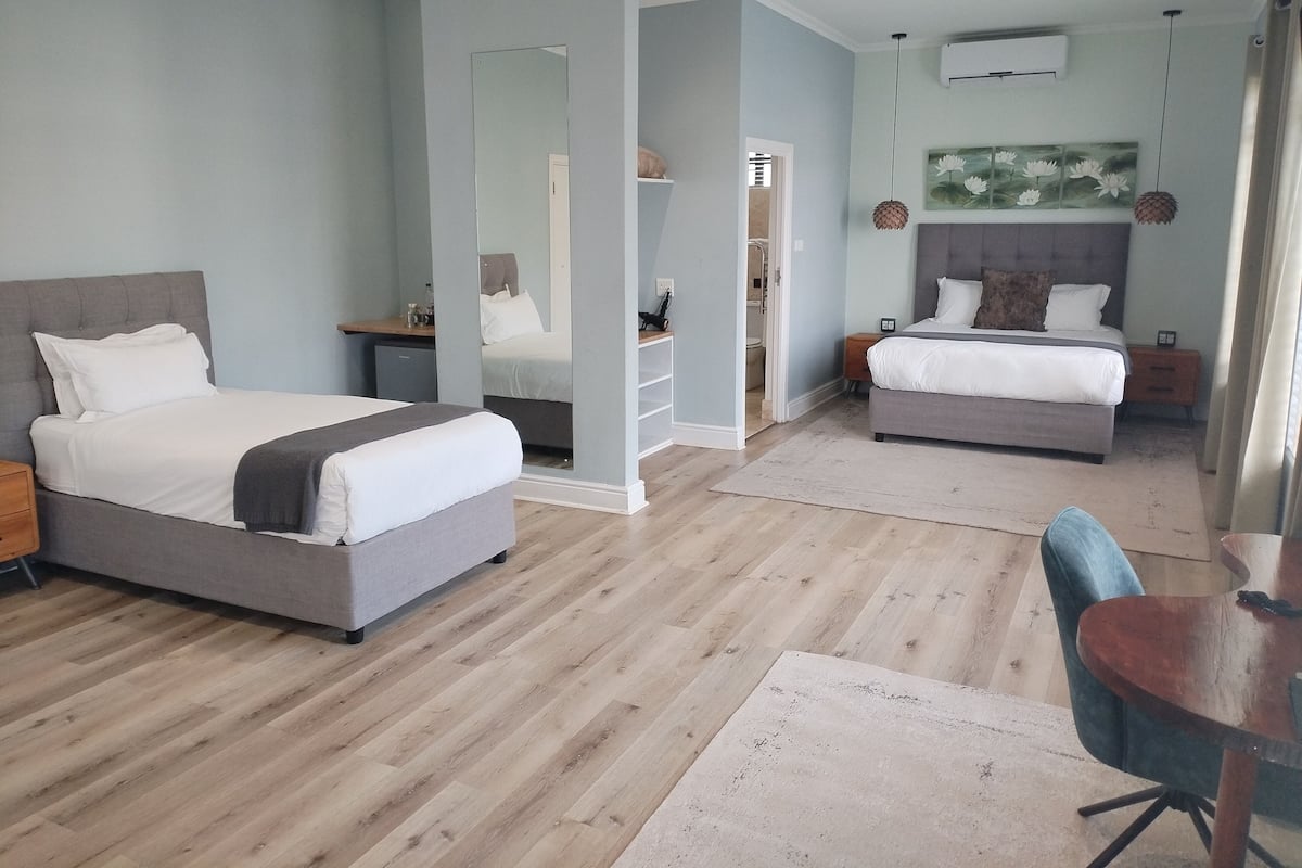 Ein modernes Schlafzimmer mit zwei Betten, Holzboden und einer kleinen Essecke.