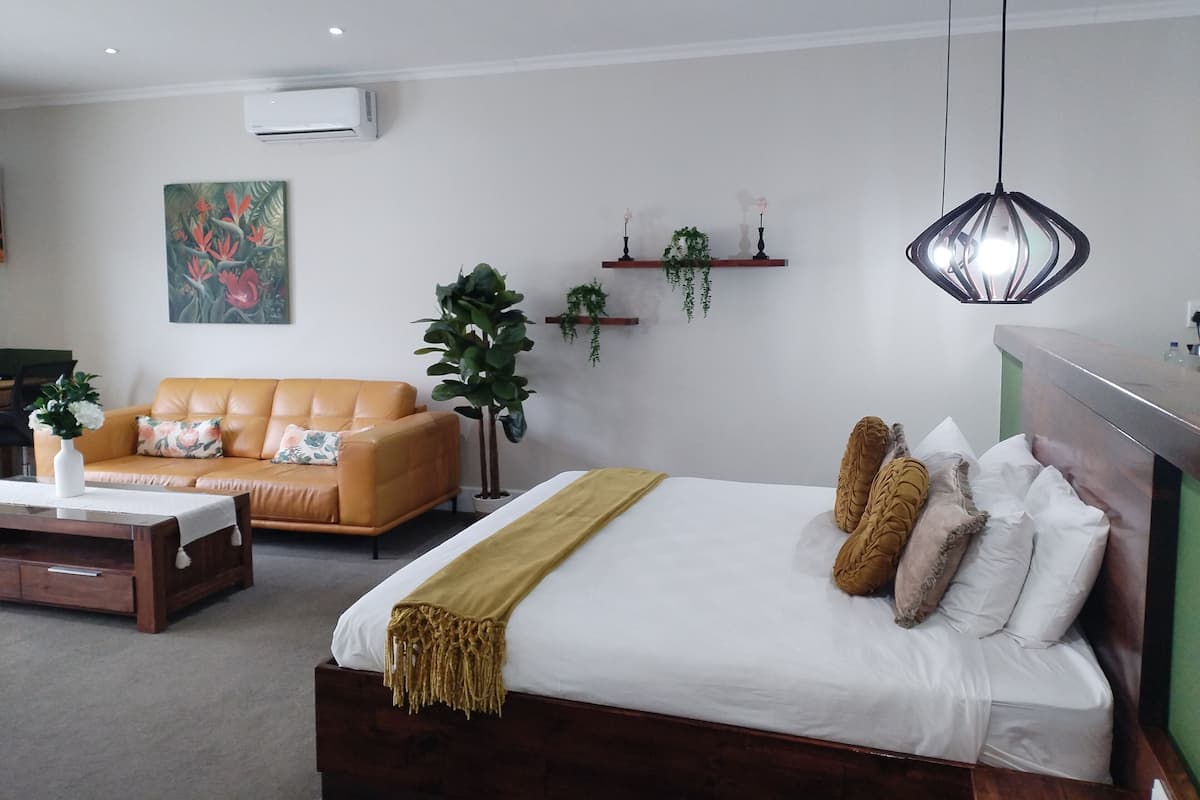 Ein modernes Schlafzimmer mit einem Bett, einer Couch, einem Couchtisch und einer Pendelleuchte.