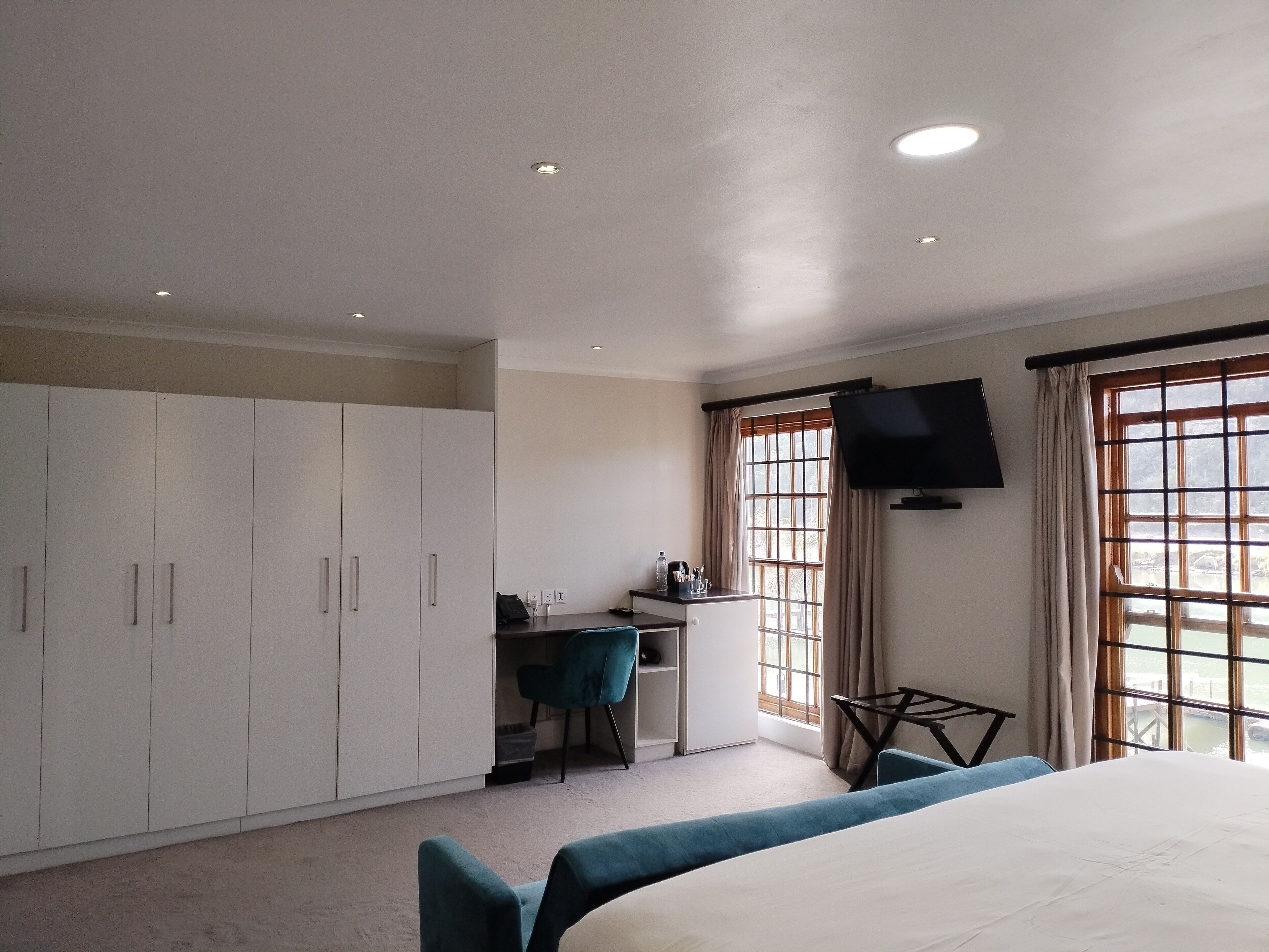 Een hotelkamer met een bed, een bureau met stoel, een aan de muur bevestigde televisie en een kledingkast.