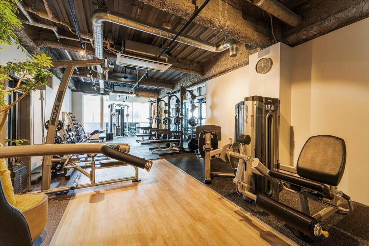 A gym with various exercise equipment, wooden flooring, and exposed ductwork on the ceiling.