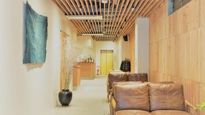 A modern interior with a wooden ceiling, a seating area with leather sofas, and a reception desk. - obi Hostel (Tokyo)