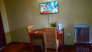 A room with a dining table, a TV mounted on the wall, a small TV on a stand, and a power outlet on the wall.