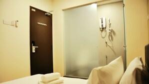Une chambre d’hôtel avec un lit, une salle de bain avec douche et une porte à clé.