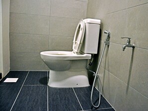 A modern bathroom with a toilet, a shower, and a tiled floor. - Gem Hotel Nusajaya (Johor Bahru)