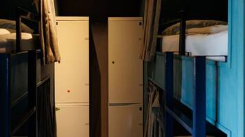 Un couloir étroit, avec des lits superposés de chaque côté, menant à une porte marquée par un point rouge.
