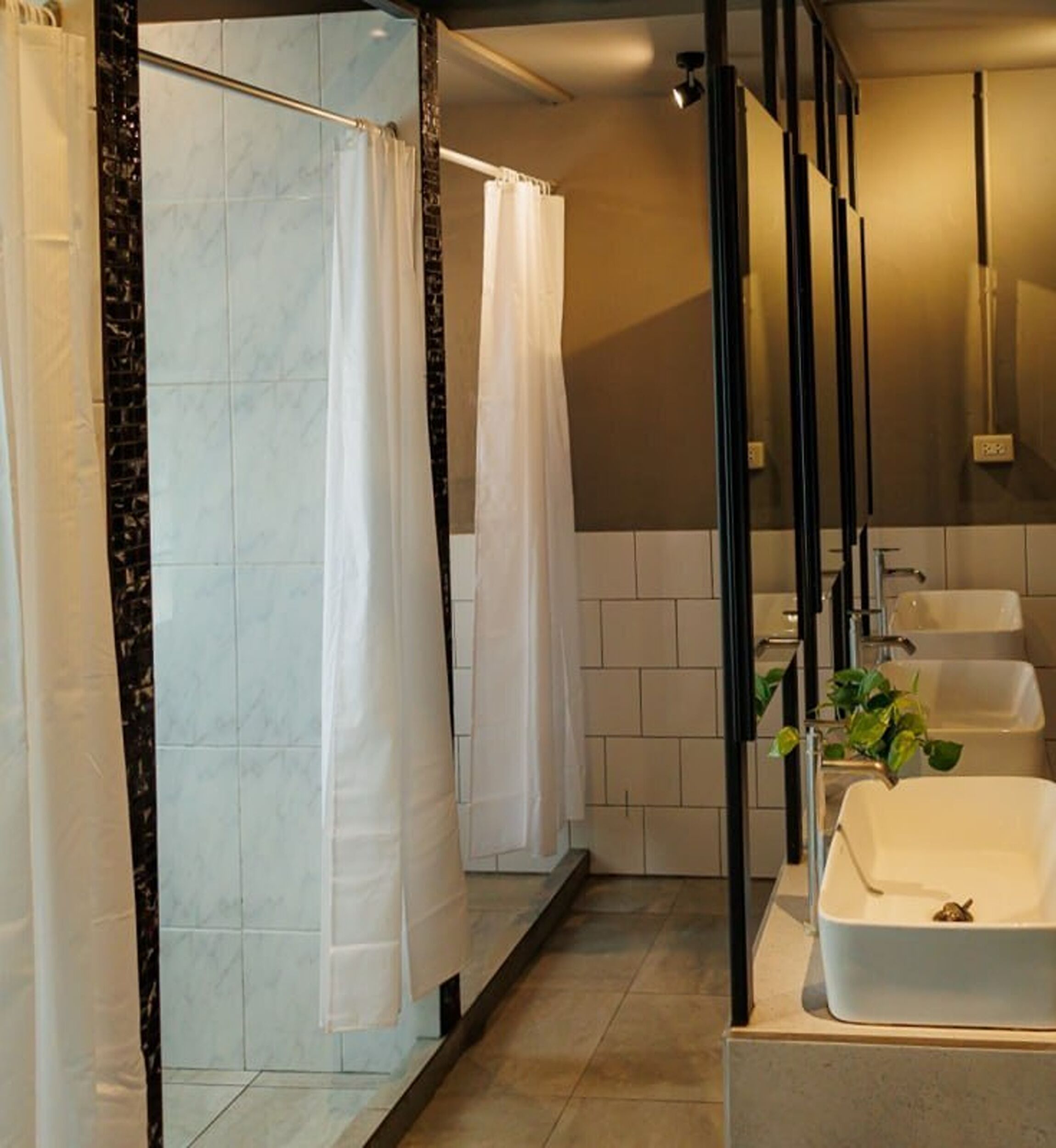 Un baño moderno con cabina de ducha, un espejo grande y un lavabo blanco.