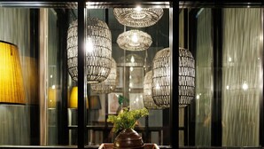 A room with multiple hanging light fixtures and a vase with green foliage on a table. - Heyyyy Bangkok - Hostel (Bangkok)