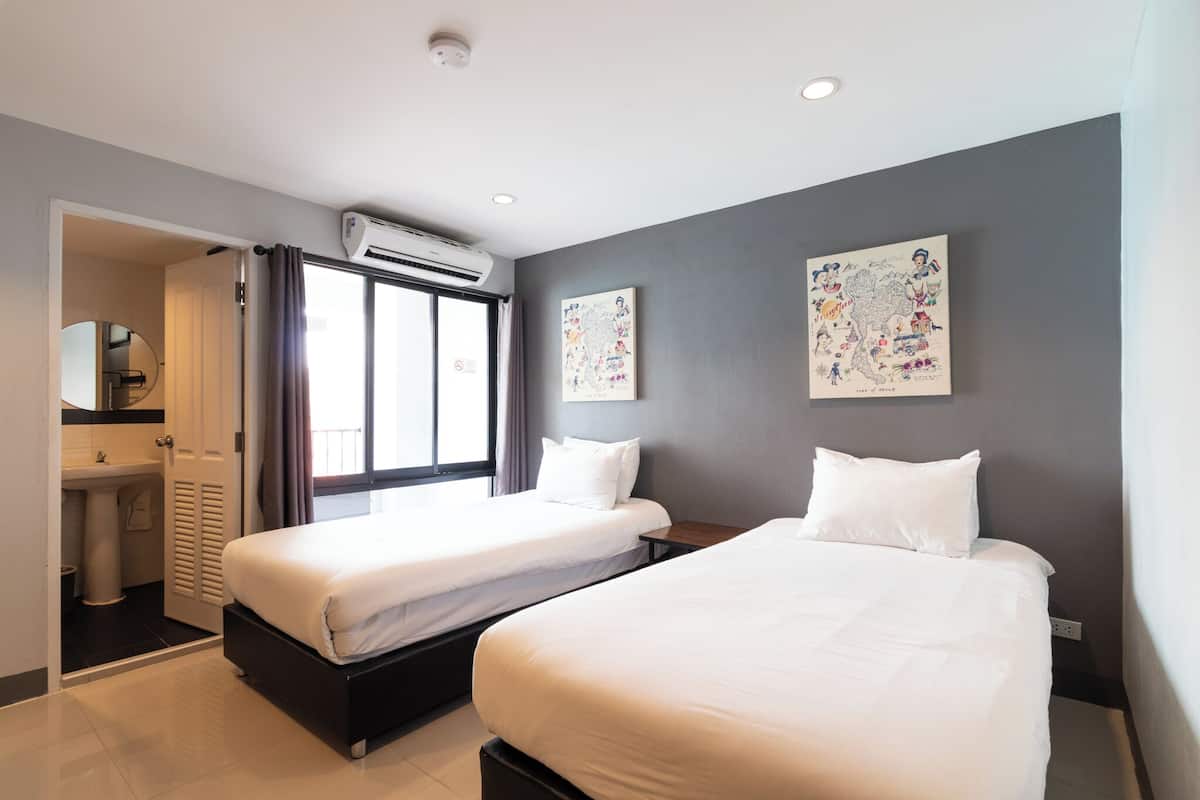 Une chambre d’hôtel avec deux lits, une salle de bain et une grande fenêtre.
