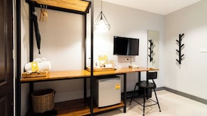 A compact room with a wooden desk, a small refrigerator, a television, and a mirror. - North Inn Town (Chiang Mai)