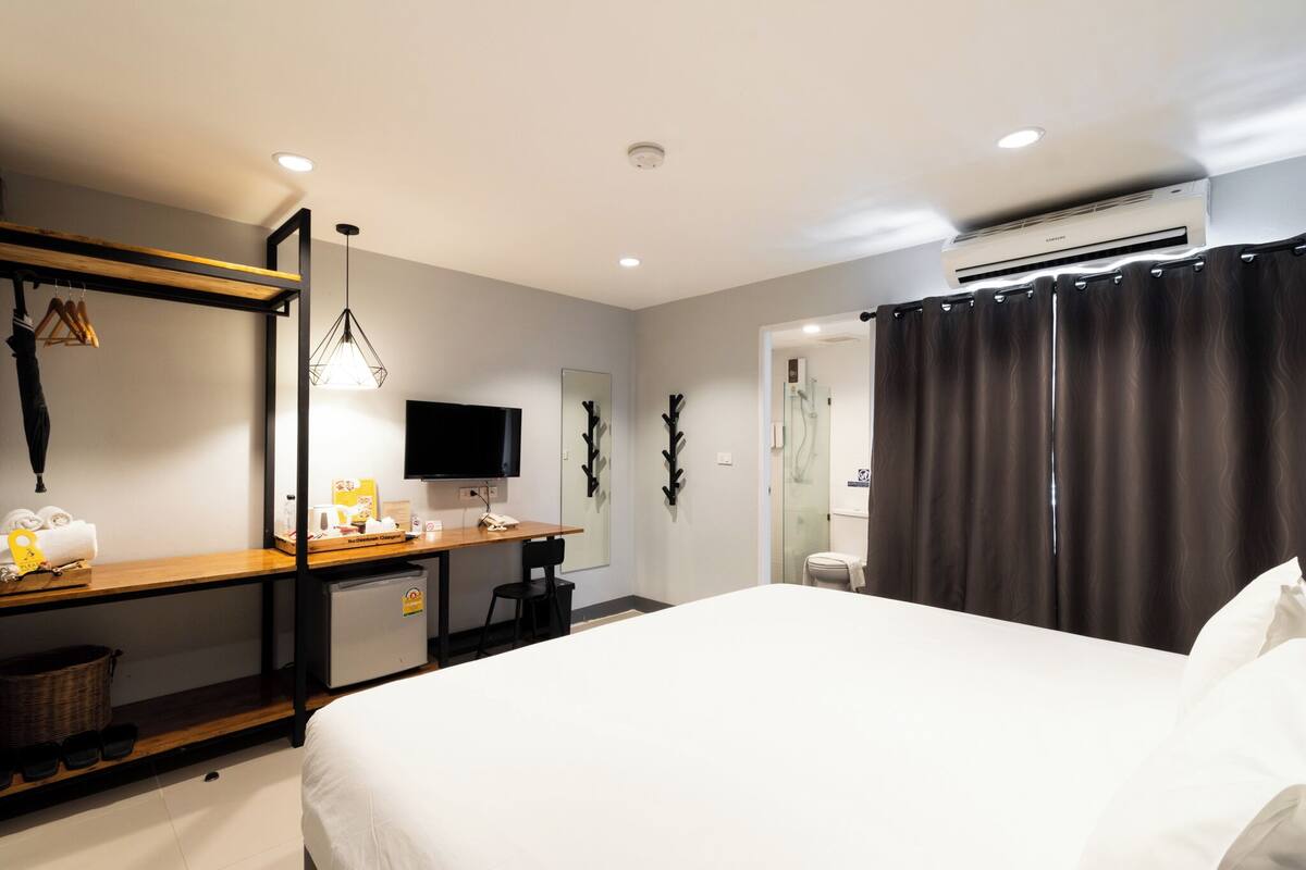 Une chambre d’hôtel équipée d’un lit, d’un bureau avec un ordinateur, d’une télévision et d’un appareil de climatisation.