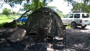 A tent set up in a natural area with a white vehicle nearby. - Matsaodi Campsite (Rakops)