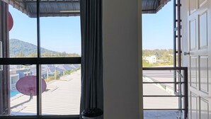 A room with a large window offering a view of a residential area and hills. - Nice Nap Hostel (Sa Khu)