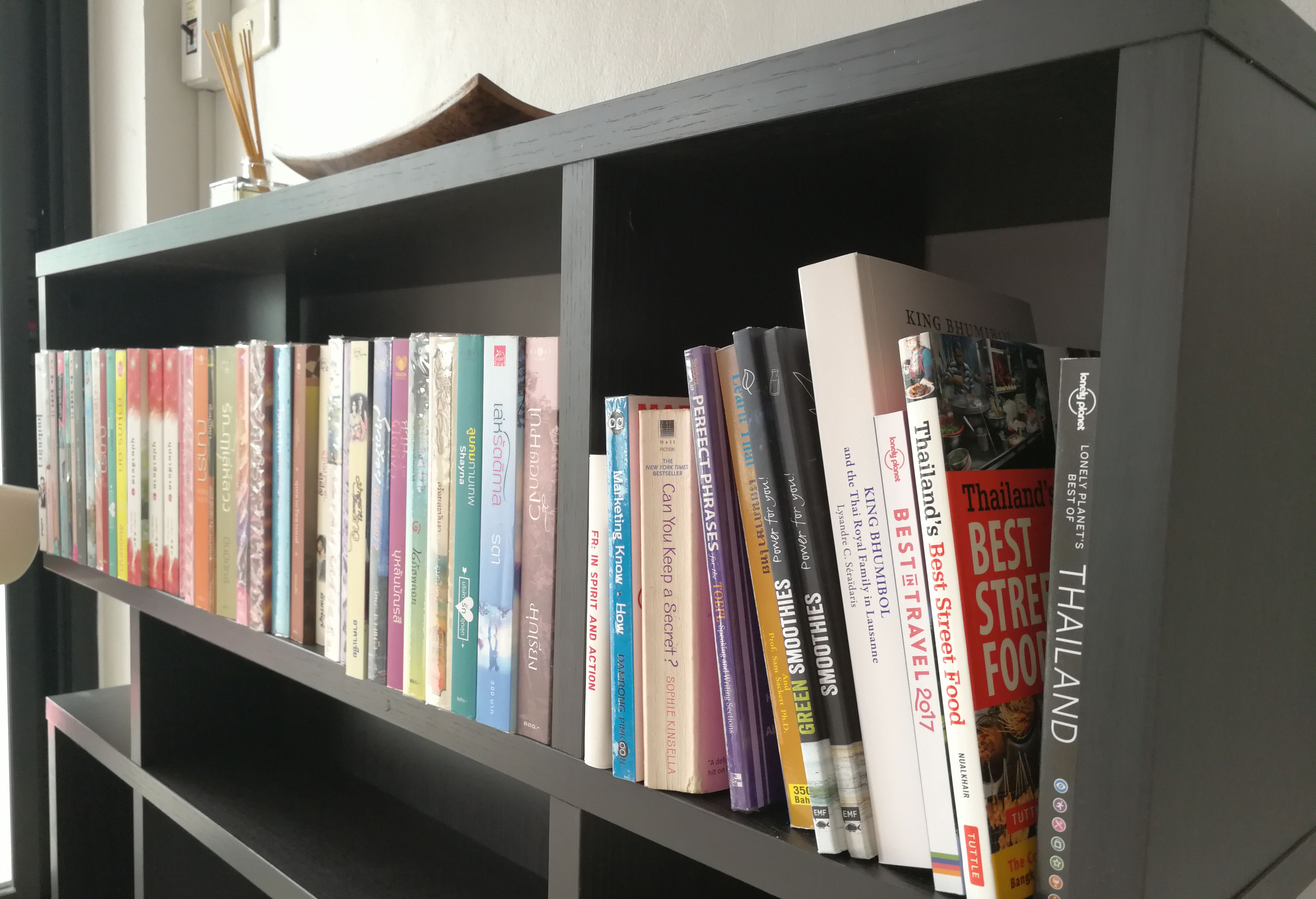 Una estantería con varios libros, incluyendo títulos como 'Thailand's Best Street Food' y 'Can You Keep a Secret?'.