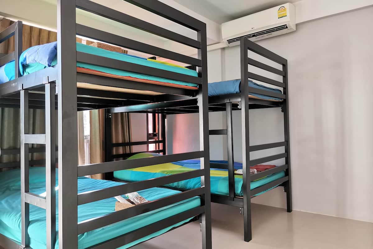 Bunk beds with blue bedding, a white wall, and an air conditioning unit.