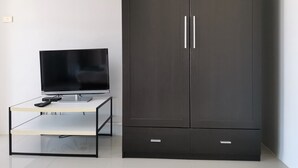 A modern room with a dark wardrobe, a glass-top table with a remote control, and a television. - Nice Nap Hostel (Sa Khu)