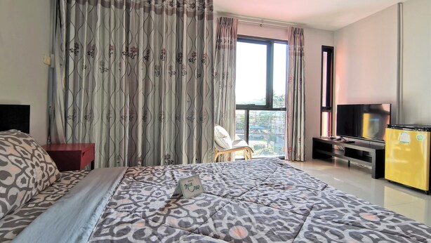 A bedroom with a large bed, a TV, a yellow refrigerator, and a window with curtains. - Nice Nap Hostel (Sa Khu)