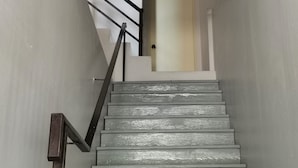 A staircase with a wooden finish and metal handrail, leading to a room with a door. - Nice Nap Hostel (Sa Khu)