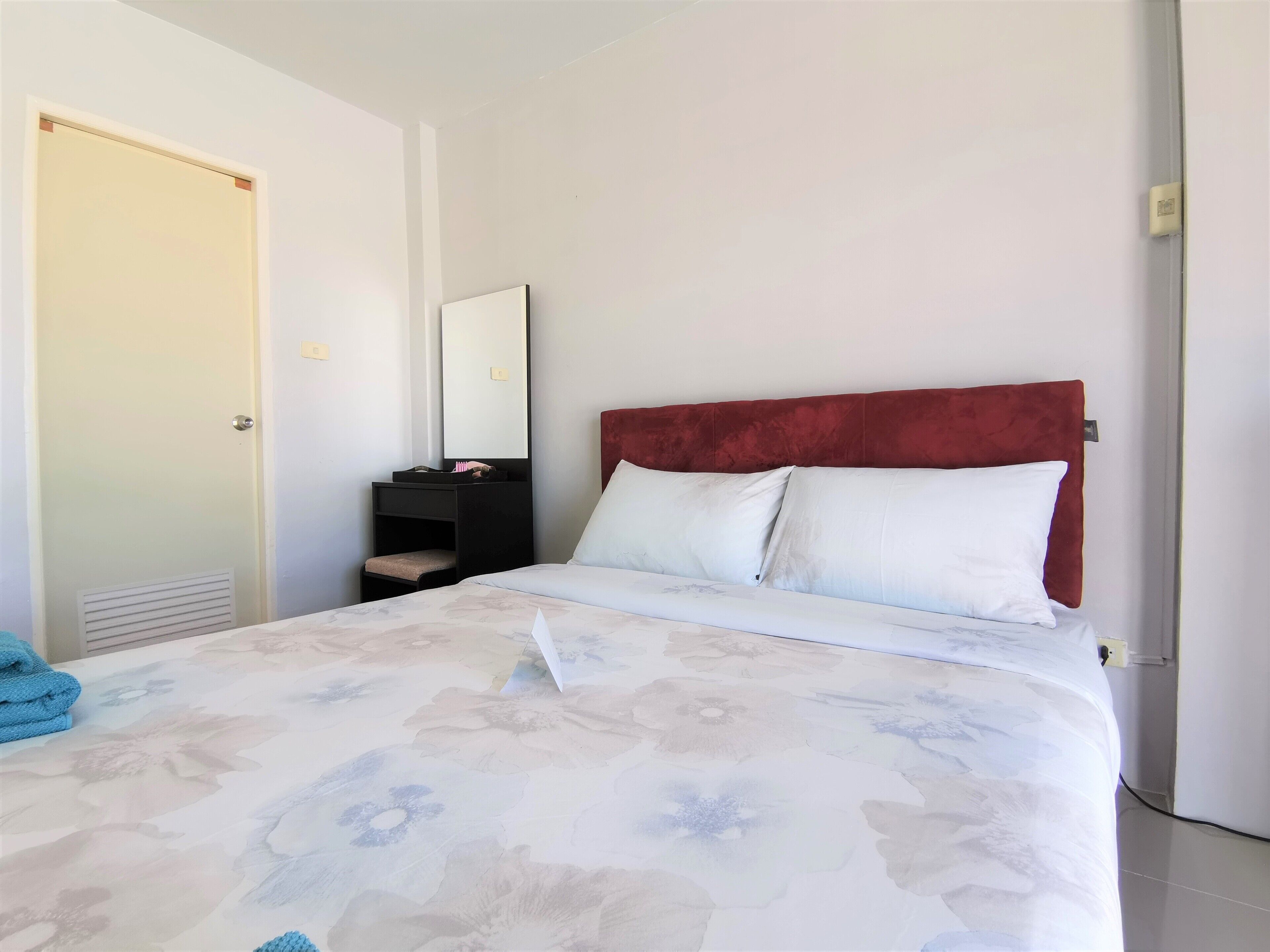 A hotel room with a bed, a bedside table, a mirror, and a wardrobe.
