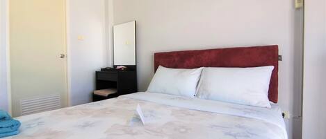 A hotel room with a bed, a bedside table, a mirror, and a wardrobe.