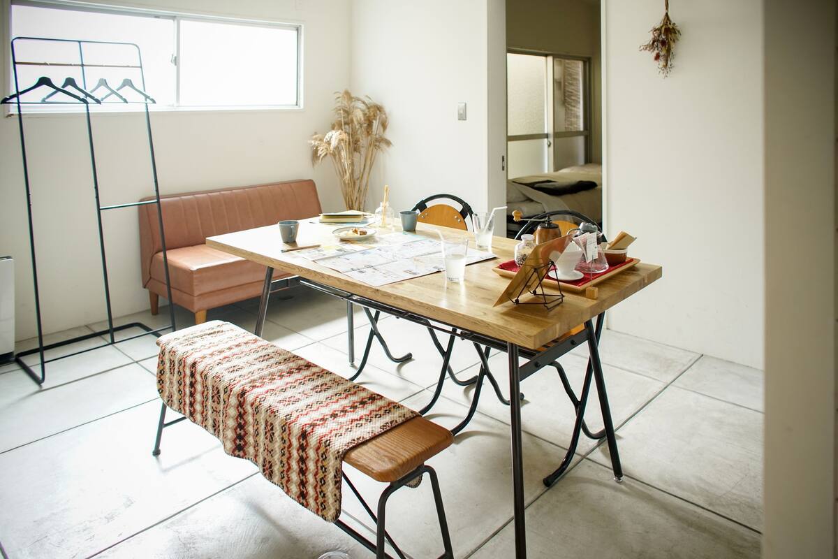 A dining area with a wooden table, benches, and a bench with a patterned cover.
