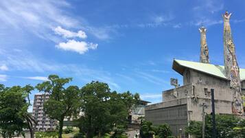 A building with a green roof and two tall spires, surrounded by trees and a clear blue sky.