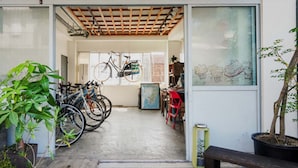 A room with bicycles parked against the wall, a potted plant, and a bench.
