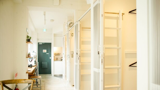 A hallway with a wooden table and chairs, a door with a sign, and a white shelving unit.