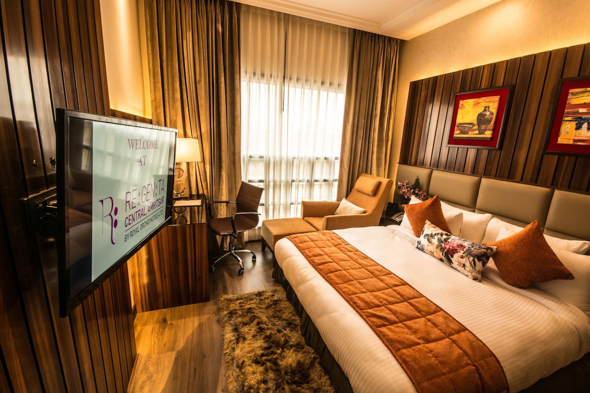 Ein Hotelzimmer mit Bett, Schreibtisch, Stuhl, Fernseher und Vorhängen.