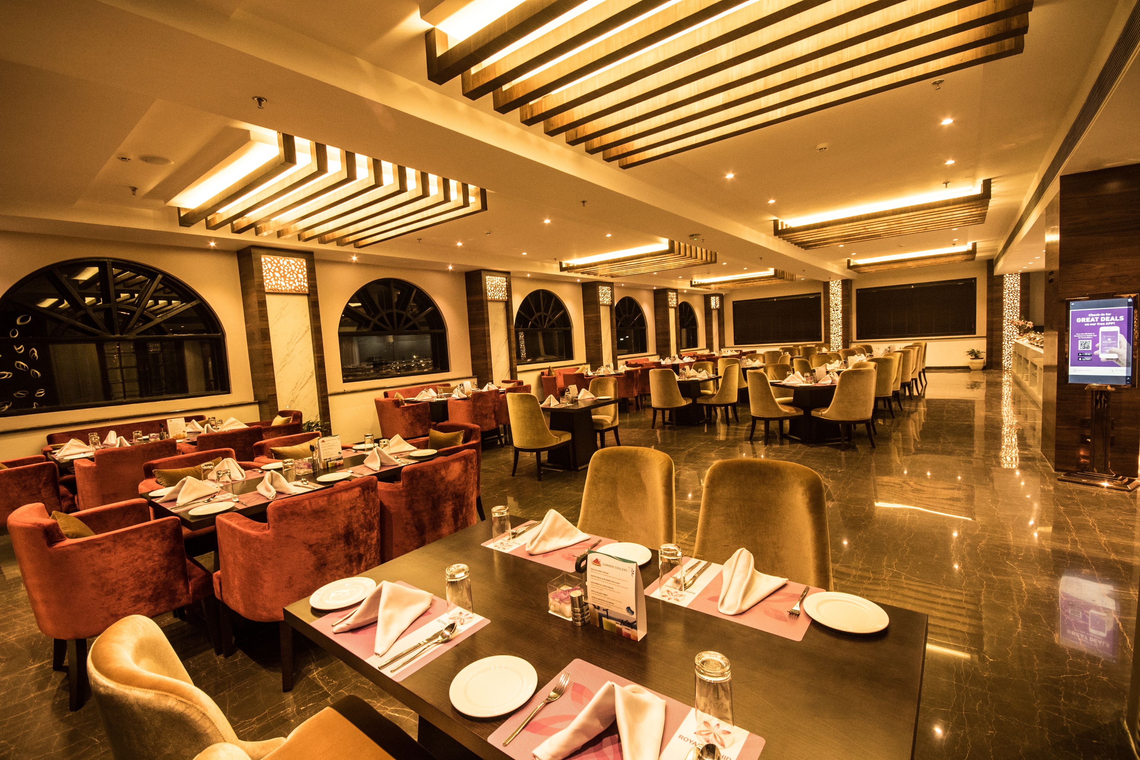 A spacious restaurant with multiple dining tables, comfortable seating, and modern lighting fixtures.
