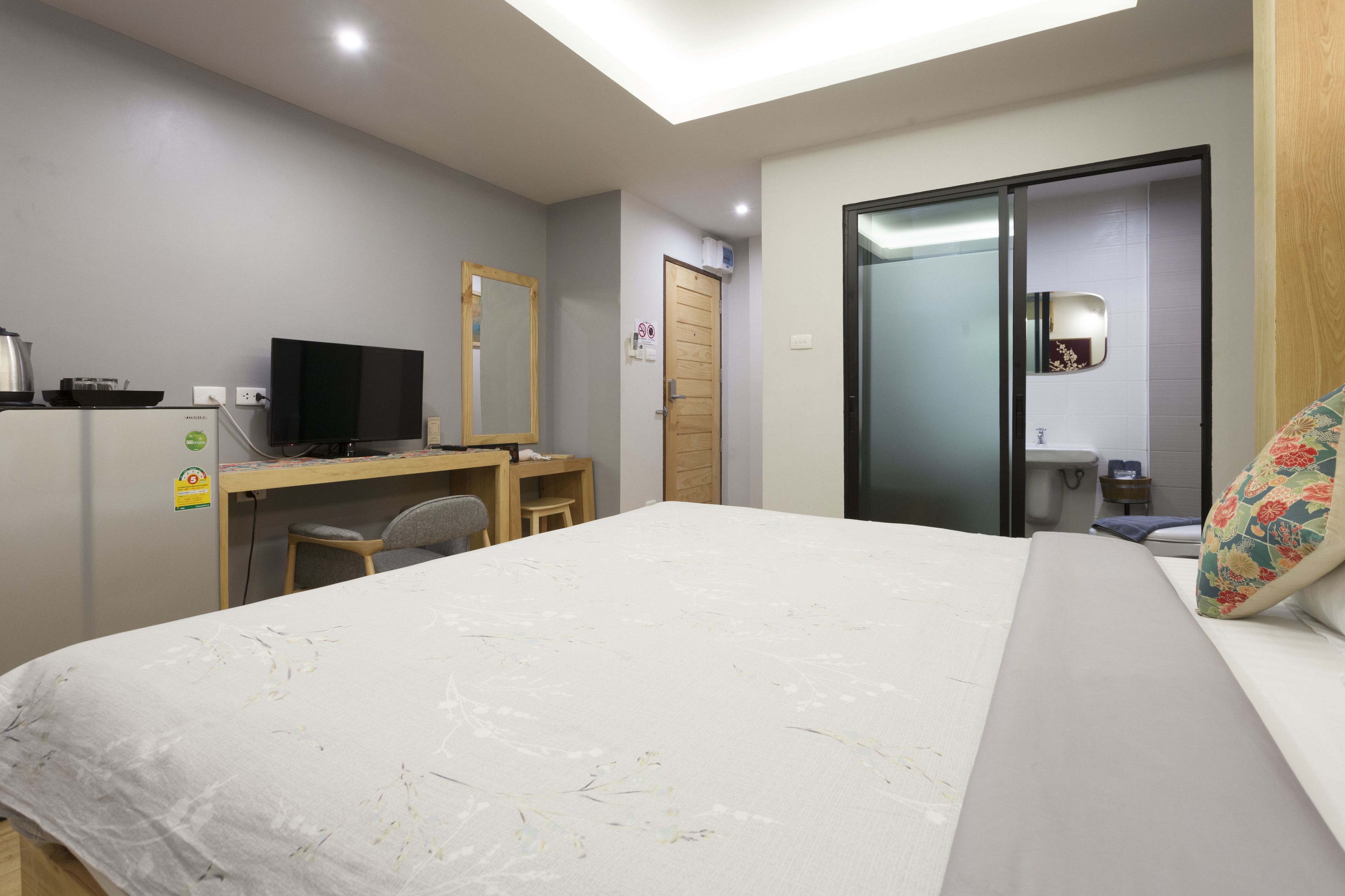 Une chambre d’hôtel avec un lit, un bureau doté d’une télévision, un miroir et une salle de bain visible à travers une porte ouverte.
