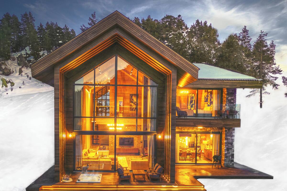 Una cabaña de troncos moderna con grandes ventanales, un interior acogedor con chimenea y un comedor.