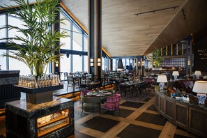 Un amplio vestíbulo de hotel con techo alto, ventanas grandes y diversas opciones de asientos.
