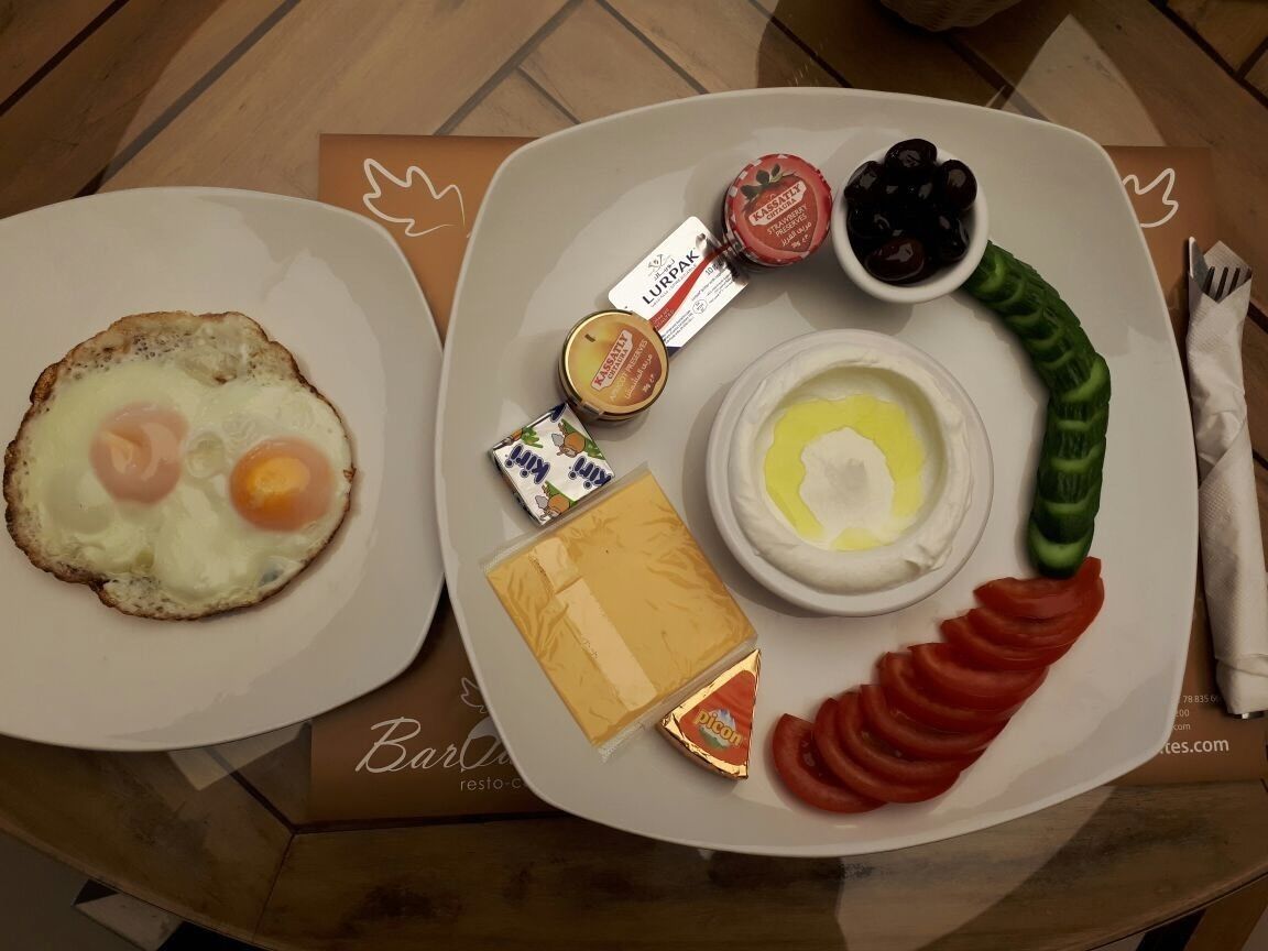 Two plates of food with various items including eggs, cheese, and sliced tomatoes.
