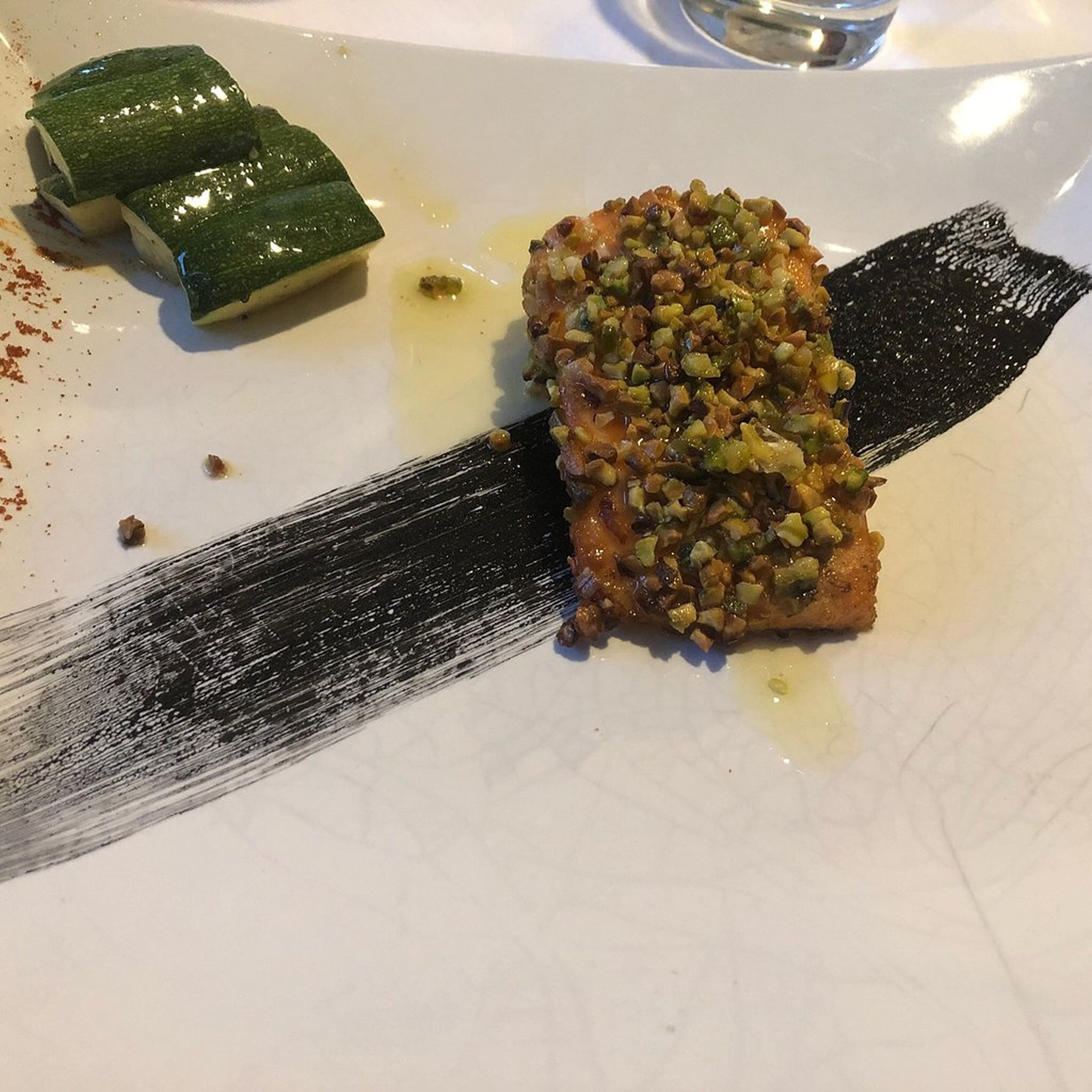 Un piatto con un boccone di cibo e un disegno a pennellata nera.