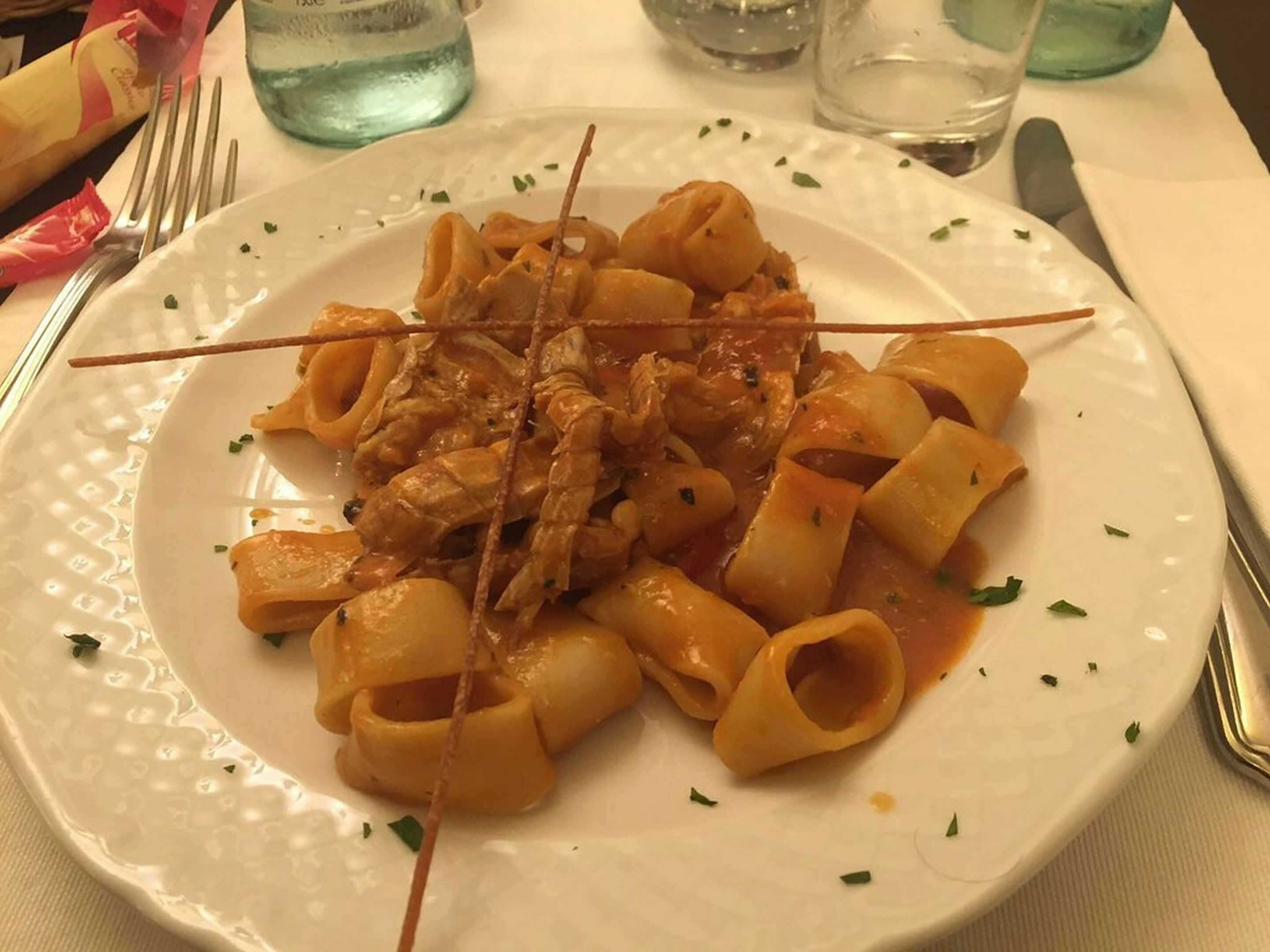 A plate of pasta with meat sauce, garnished with herbs, on a white plate.