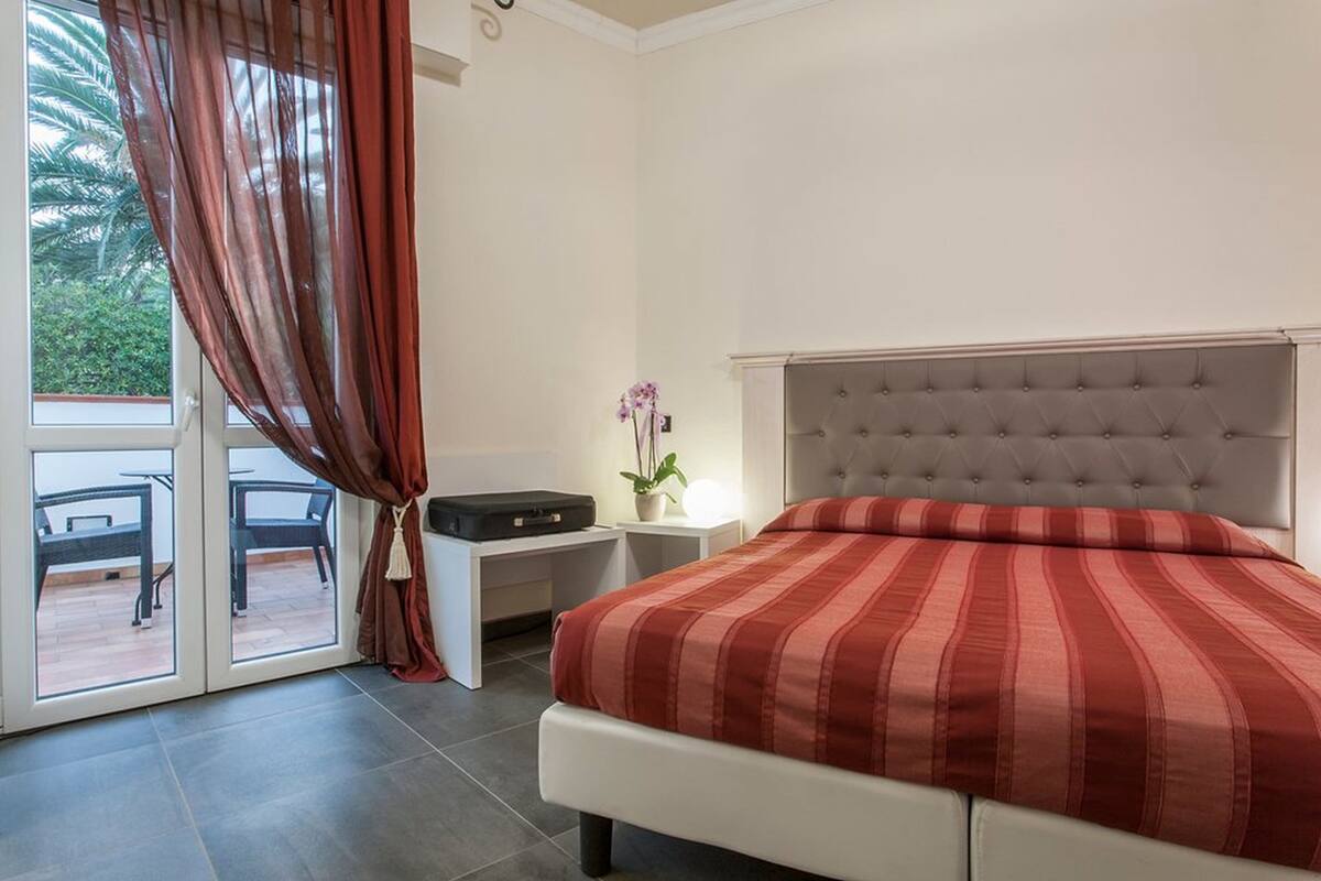 A bedroom with a bed, a nightstand, a desk, and a chair.
