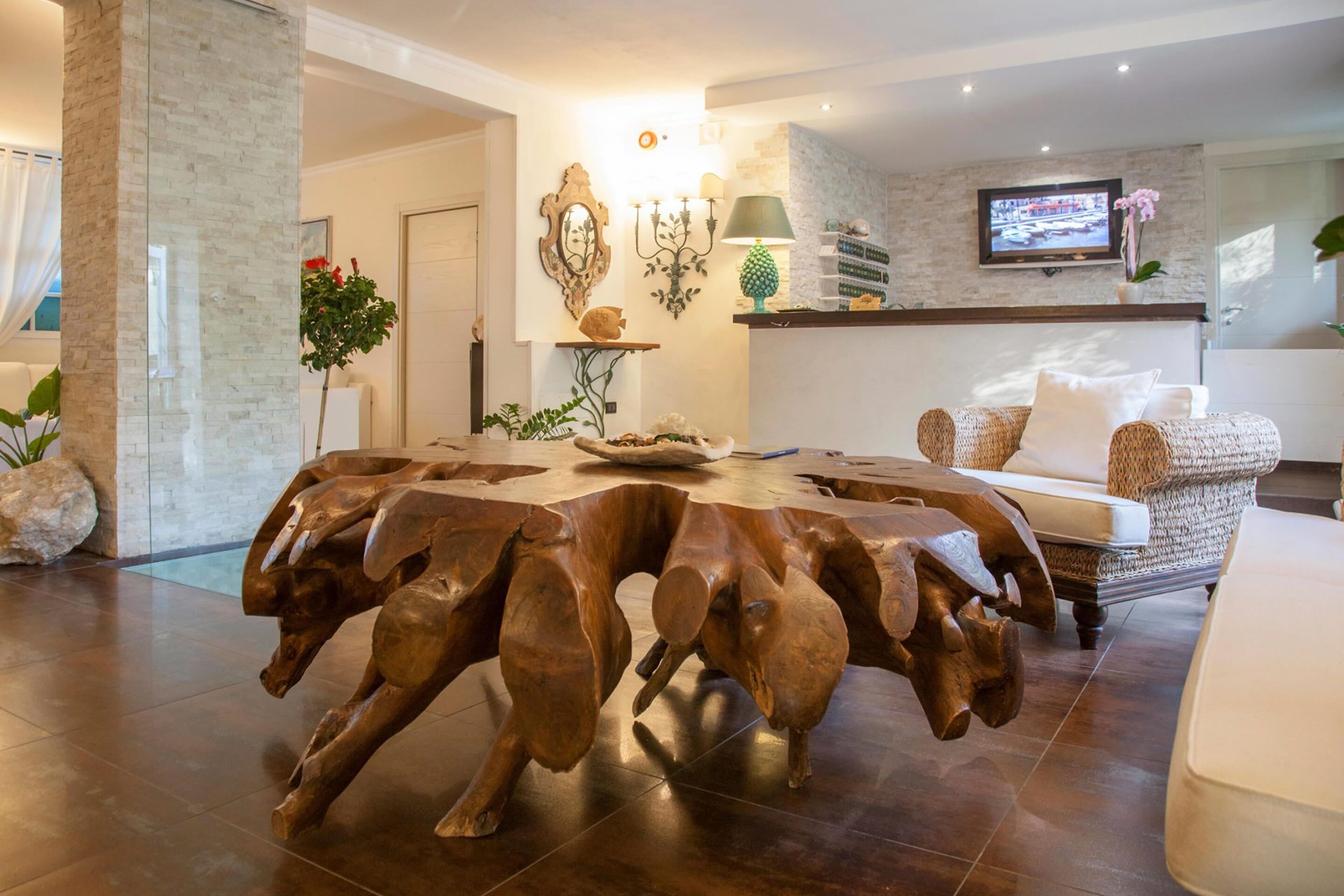 Een moderne woonkamer met een bijzondere houten salontafel, een comfortabele bank en een aan de muur bevestigde televisie.