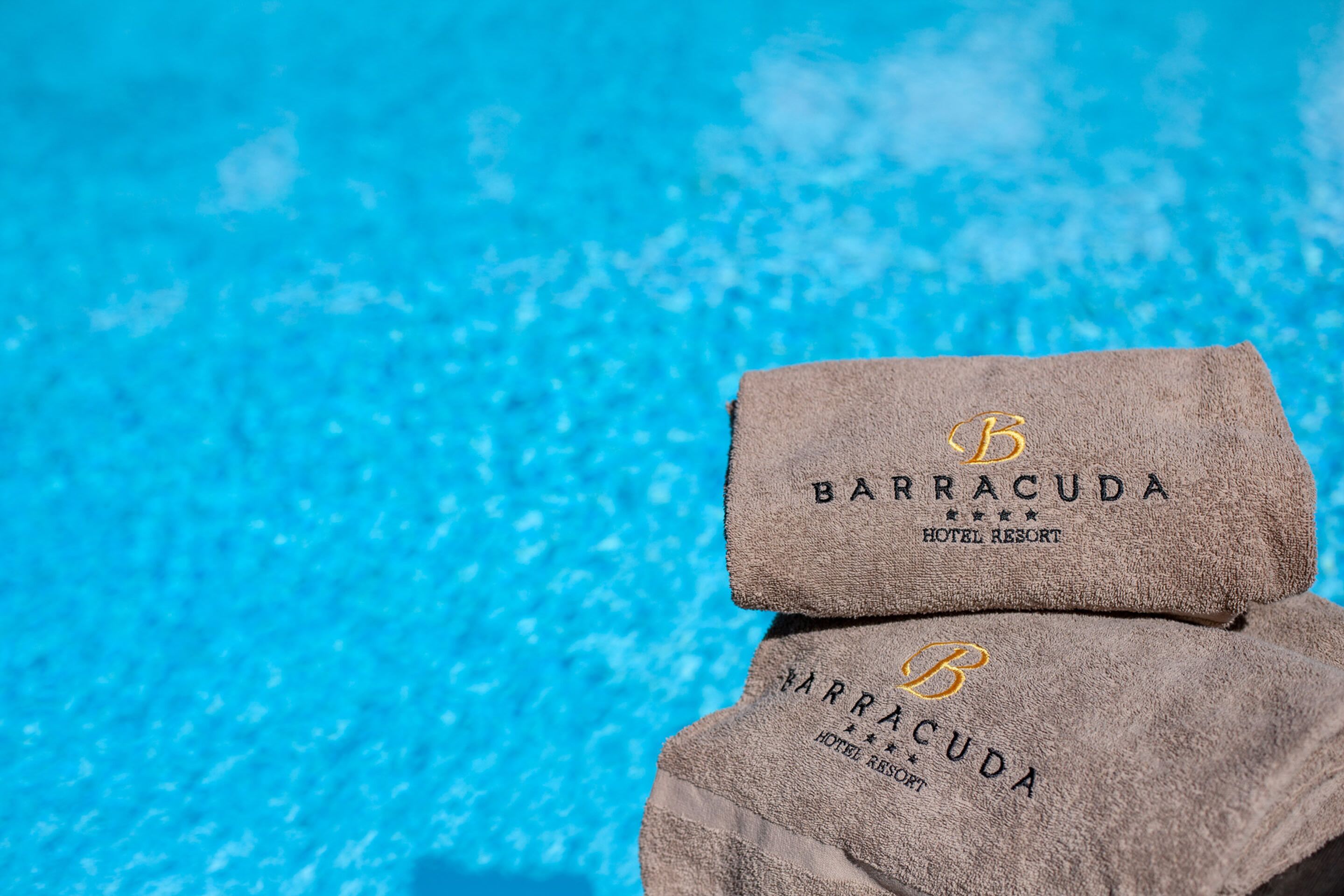 Two towels with the Barracuda Hotel Resort logo.