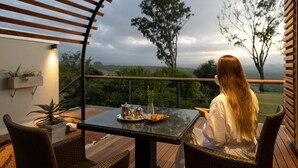 A balcony with a table set for two, featuring a view of the landscape.