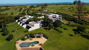 A large, modern house with multiple rooms, a swimming pool, and a well-maintained lawn.