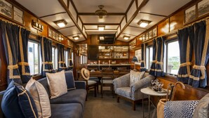A train's interior with a dining area, sofas, and a table with glasses.